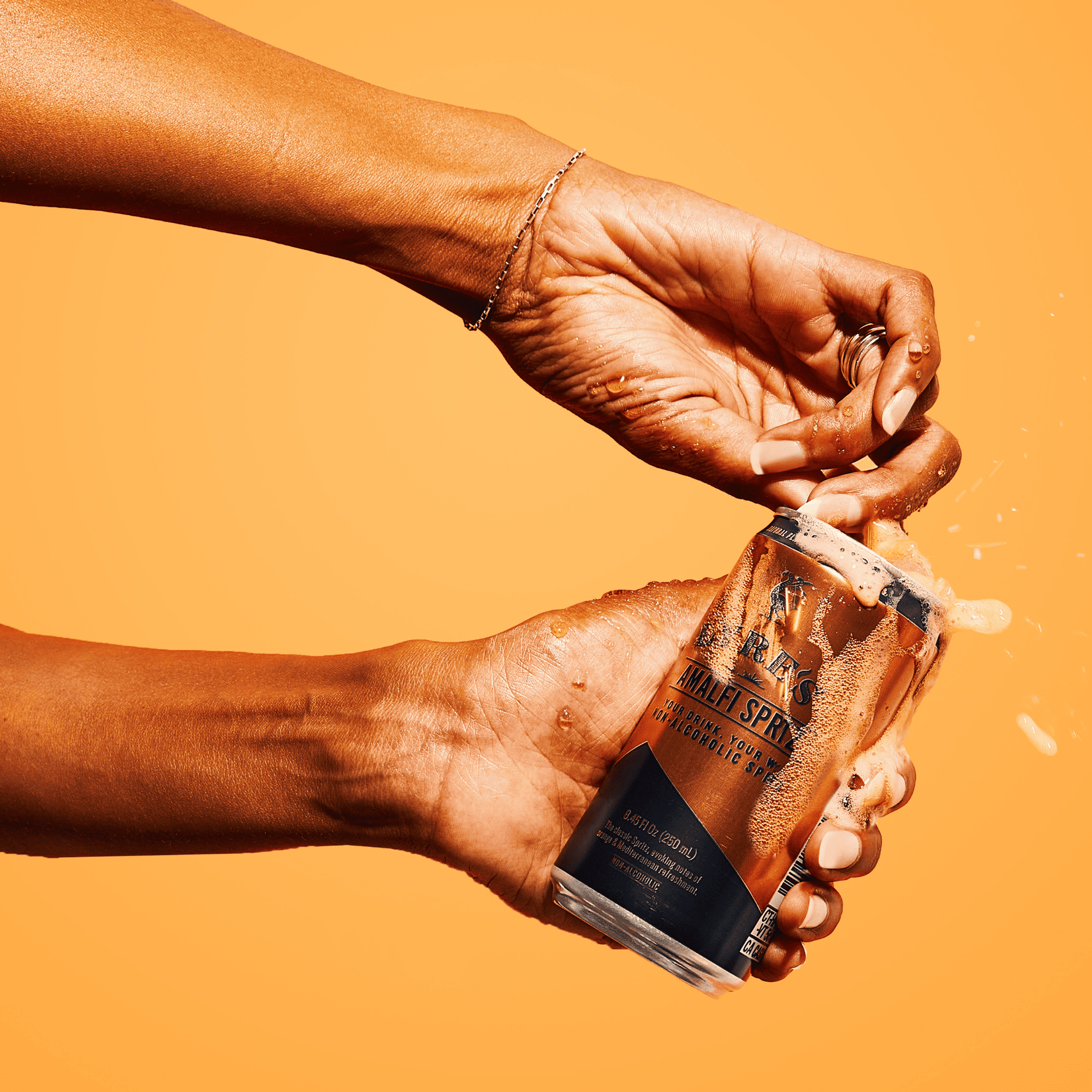 Hand holding Lyre's Amalfi Spritz non alcoholic cocktail in a can against an orange background